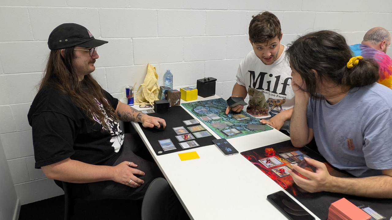 People playing a board game together at a table with various game pieces and a bottle.
