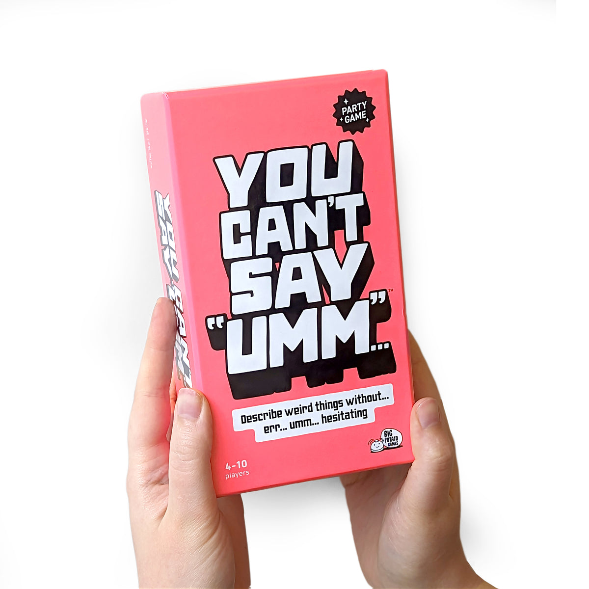 Pink game box titled 'You Can't Say Umm' held by a hand on a white background