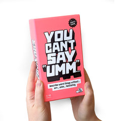 Pink game box titled 'You Can't Say Umm' held by a hand on a white background